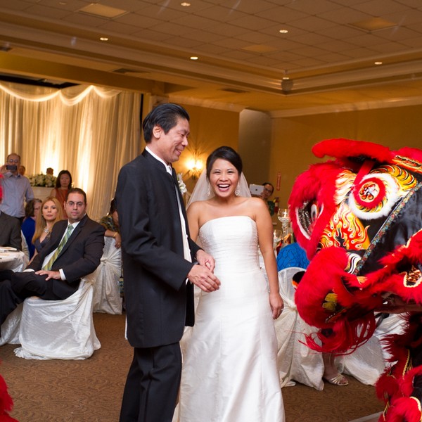 Picture of an Asian couple celebrating their wedding, with lion dancers inside a ballroom