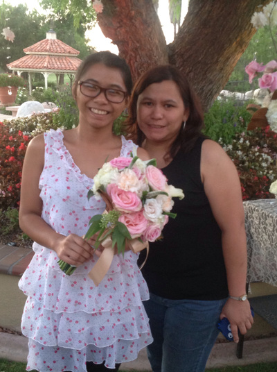 Smiling mother with her daughter holding a bouquet in a garden setting