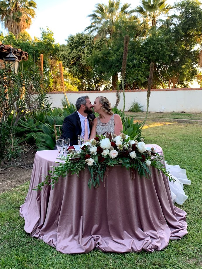 Picture of a couple kissing while seated at their sweetheart table at the Redlands Assistencia