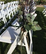 Picture of ceremony chairs lined up, with floral arrangements tied to the chairs