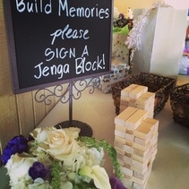 Picture of a guest sign-in table, with two Jenga games, and a sign saying 