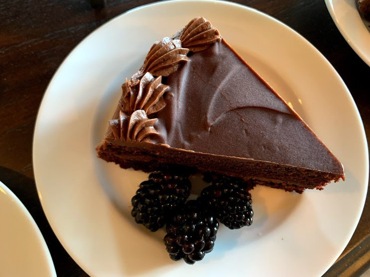 Picture of a slice of chocolate ganache cake plated with fresh blackberries