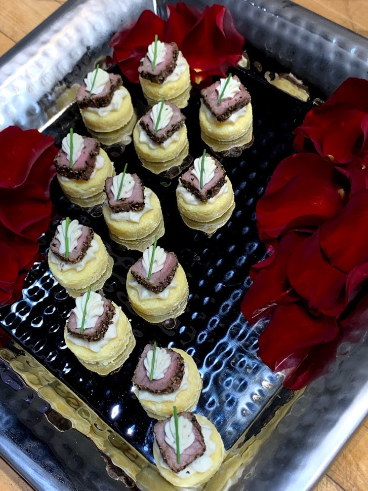 Beef & polenta canapes on a tray with rose petals