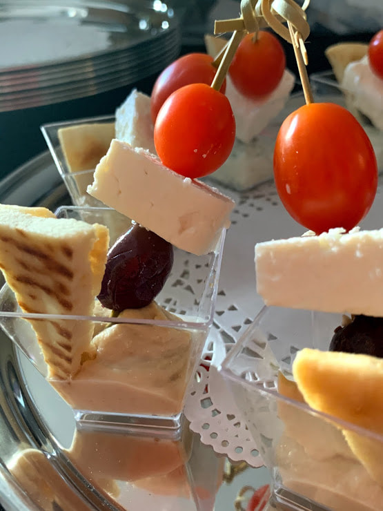 close-up picture of Mezze shots - house-made hummus, pita chips, and caprese skewer in a shot glass