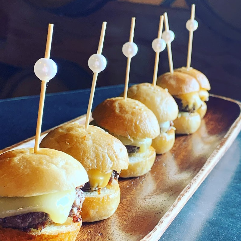 Mini cheeseburger sliders with pearl picks on a wood tray