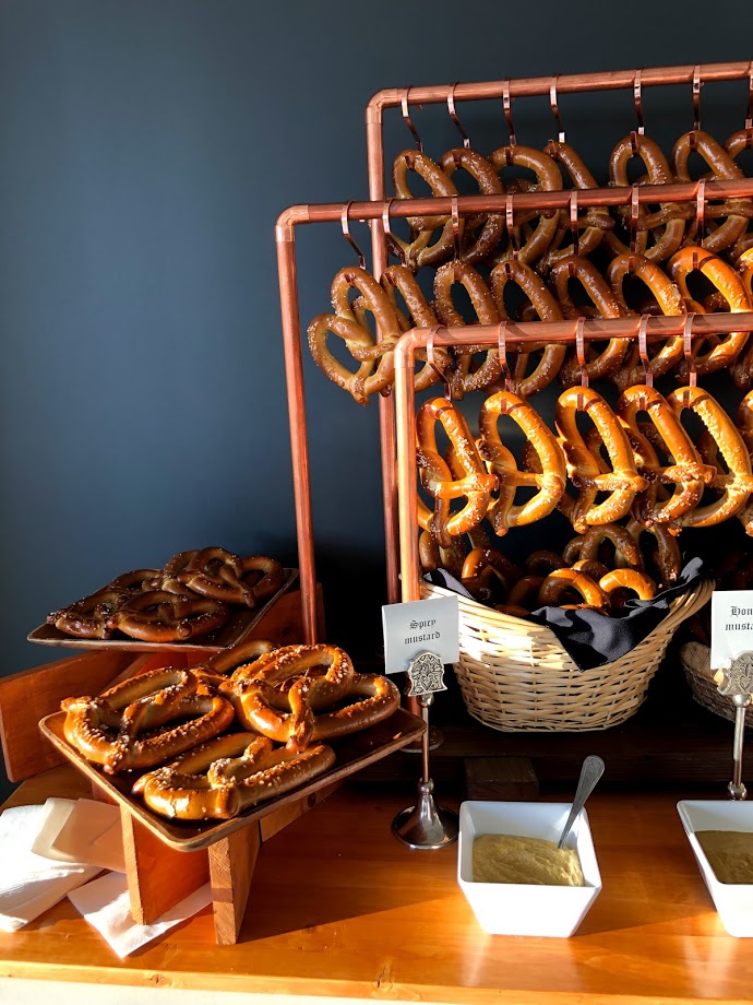 Pretzel bar with copper three-tiered stand, pretzels hanging from hooks and in baskets