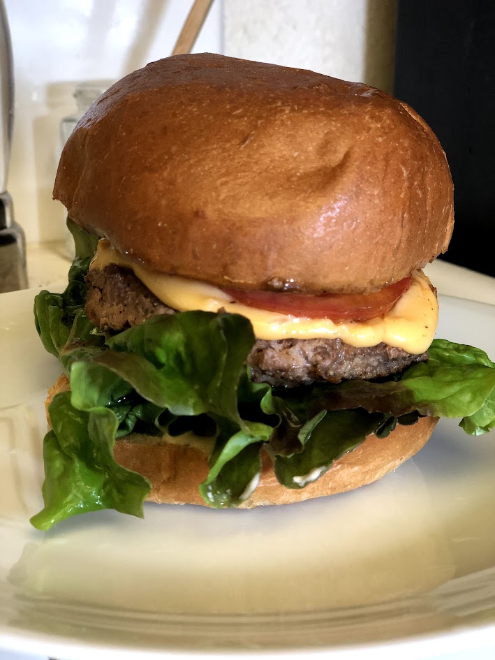 Picture of burger on brioche with lettuce, cheese and tomato