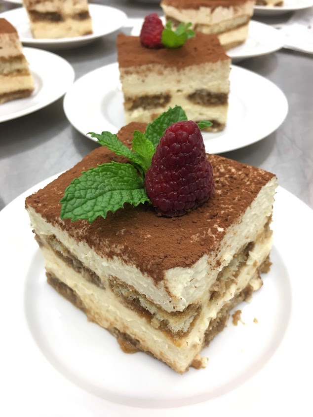 Tiramisu, plated, topped with a fresh raspberry and sprig of mint
